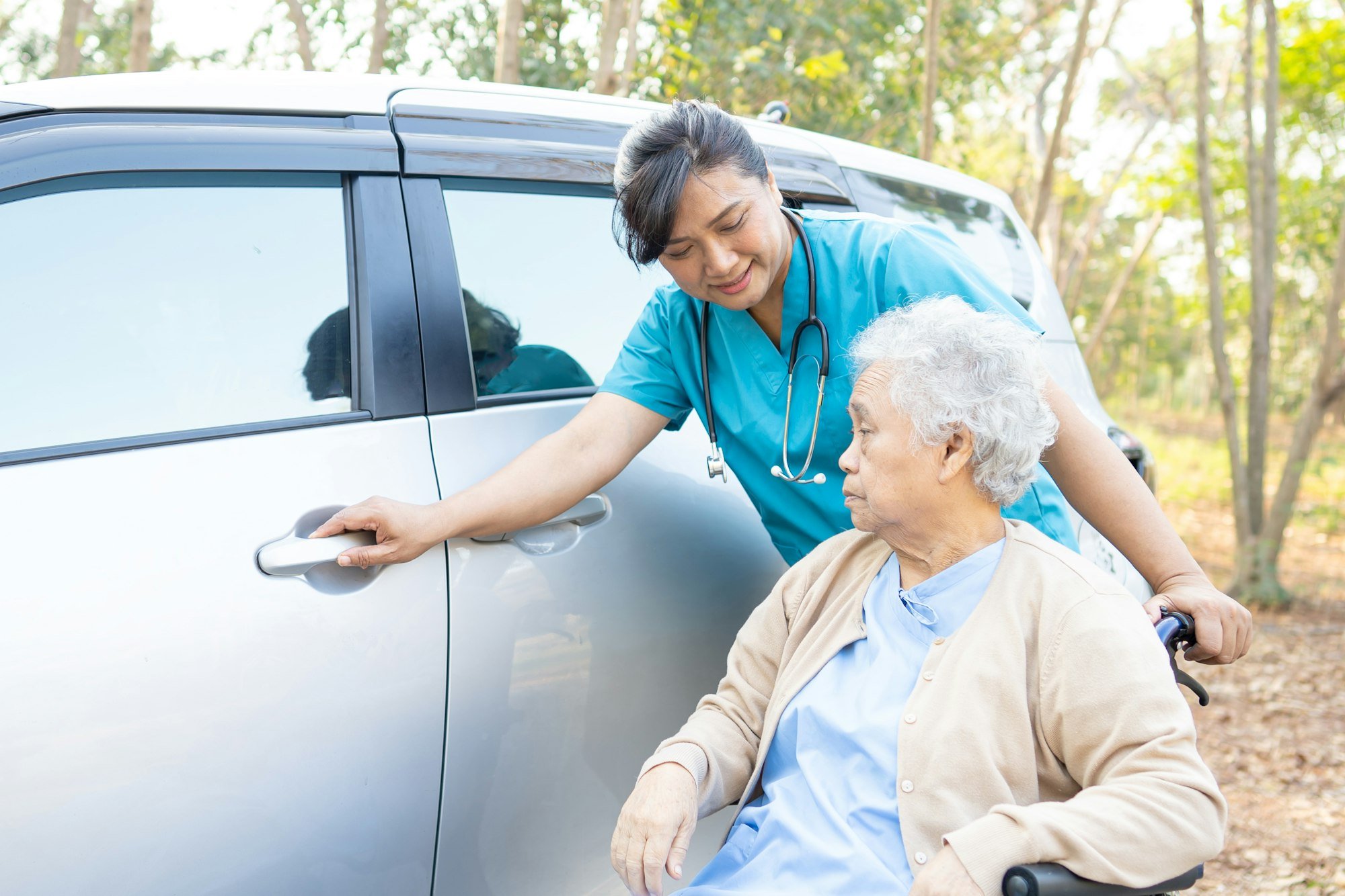 Help and support asian elderly woman patient sitting on wheelchair prepare get to her car.