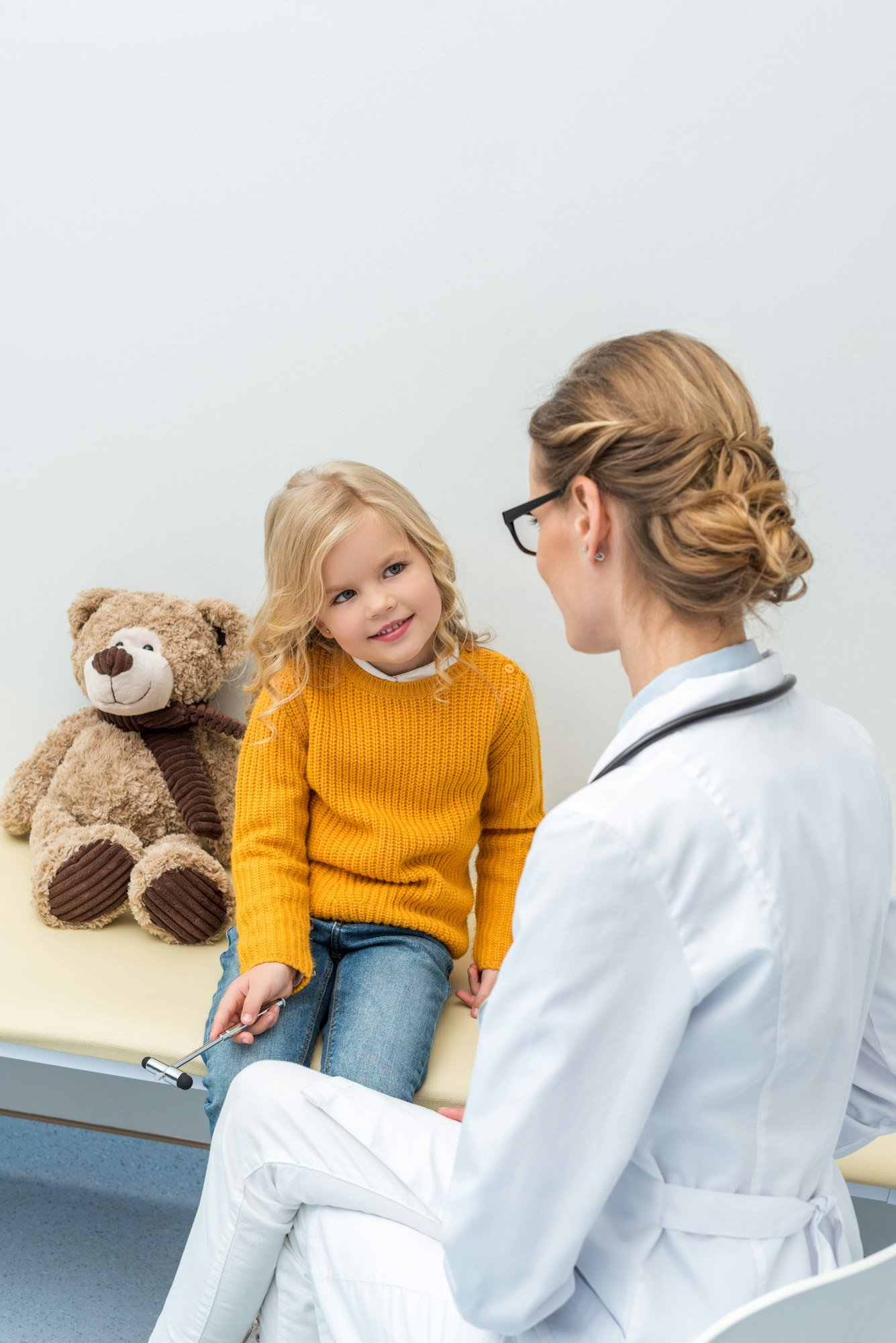 smiling little girl doing neurology examination for female doctor