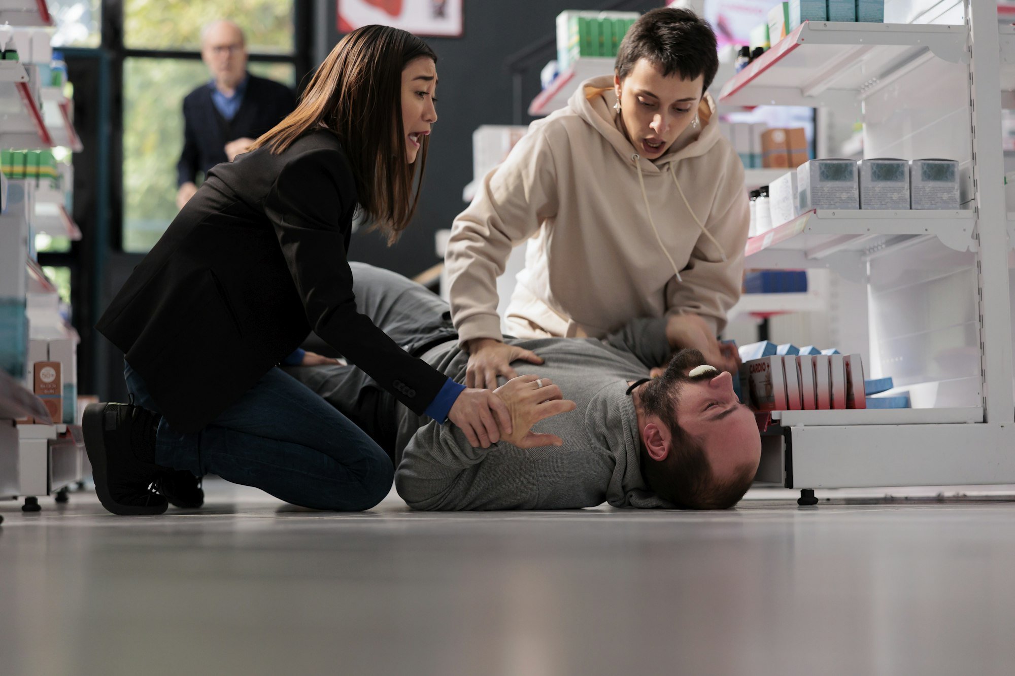 Women standing on knees near unconscious man with epilepsy