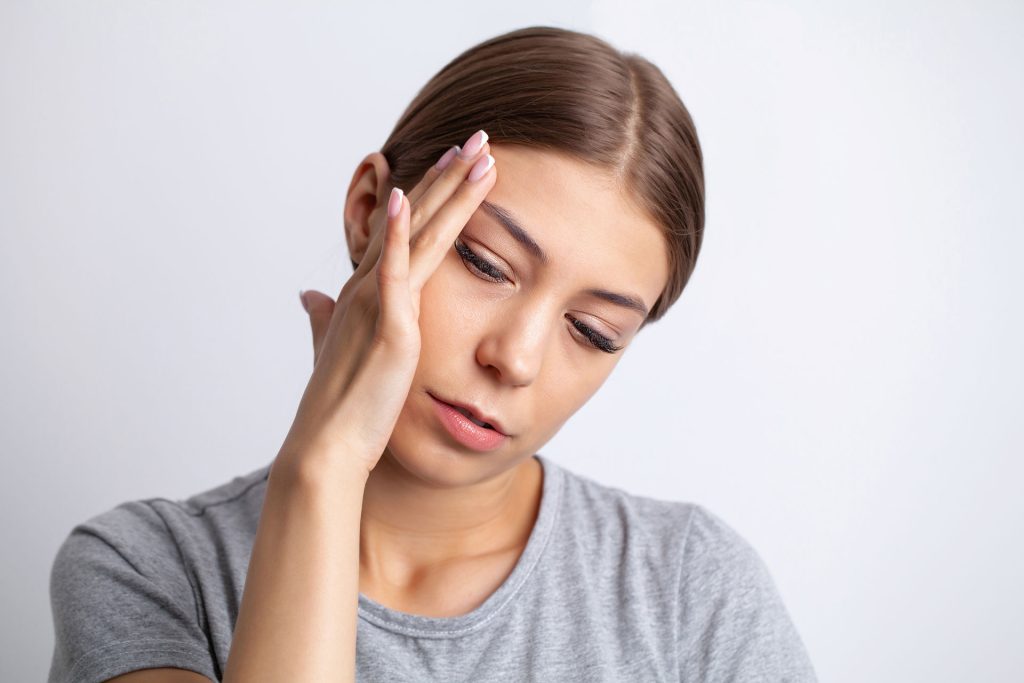 A young woman touching her head.